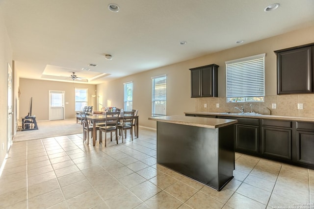 kitchen featuring decorative backsplash, a center island, a sink, a tray ceiling, and recessed lighting
