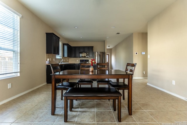 dining room with baseboards, light tile patterned floors, and a healthy amount of sunlight