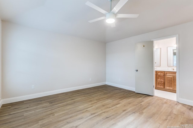unfurnished bedroom with ceiling fan, baseboards, ensuite bathroom, and light wood-style flooring
