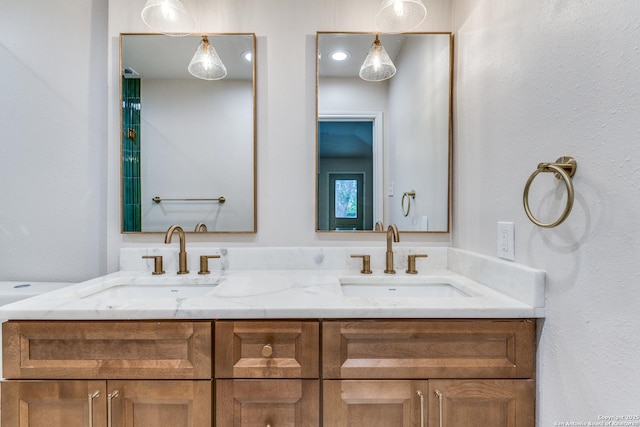 bathroom featuring a sink, a textured wall, and double vanity