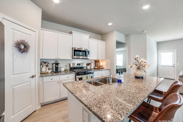 kitchen featuring a sink, light stone counters, a kitchen island with sink, and stainless steel appliances