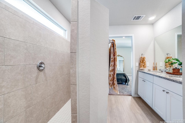 ensuite bathroom with visible vents, wood finished floors, vanity, connected bathroom, and tiled shower