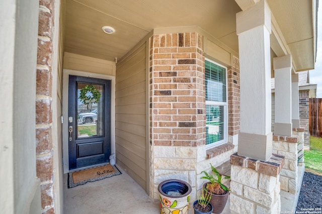 doorway to property featuring a porch and brick siding