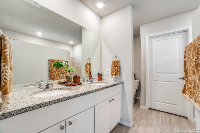 bathroom with double vanity, a sink, wood finished floors, and toilet