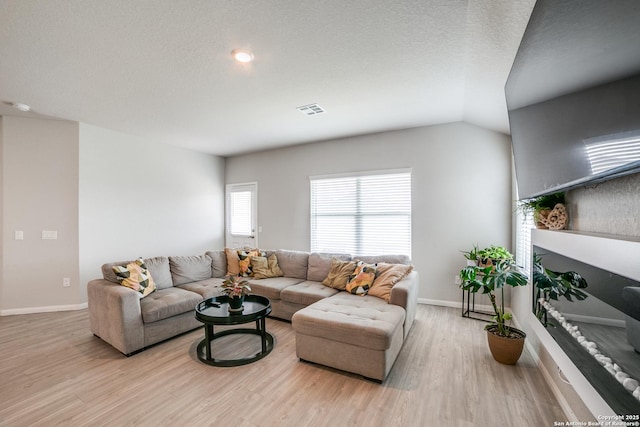 living area with baseboards, visible vents, and wood finished floors