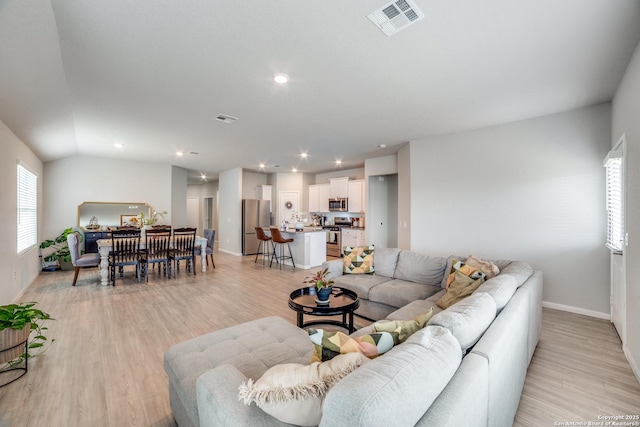 living area with baseboards, light wood-type flooring, and visible vents