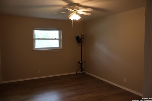 spare room with dark wood-style flooring, ceiling fan, and baseboards