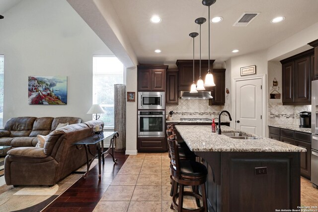 3811 Valencia Ct, San Antonio, TX 78259 - kitchen with stainless steel appliances, a sink, open floor plan, dark brown cabinets, and recessed lighting