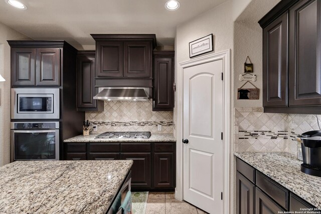 3811 Valencia Ct, San Antonio, TX 78259 - kitchen featuring appliances with stainless steel finishes, ventilation hood, backsplash, light stone counters, and recessed lighting