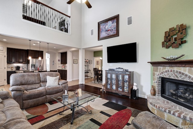 3811 Valencia Ct, San Antonio, TX 78259 - living room with dark wood-type flooring, a ceiling fan, a stone fireplace, baseboards, and a towering ceiling