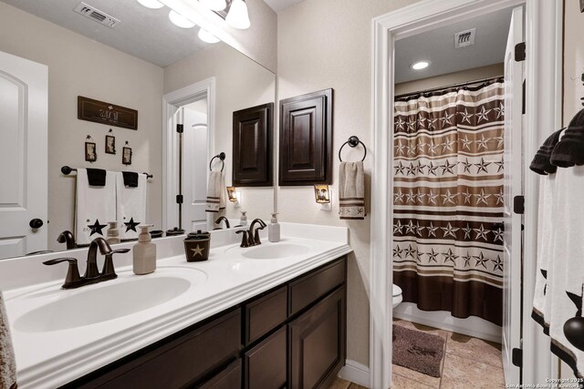3811 Valencia Ct, San Antonio, TX 78259 - bathroom with toilet, double vanity, curtained shower, and stone finish floors