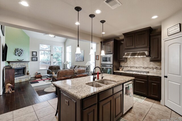 3811 Valencia Ct, San Antonio, TX 78259 - kitchen featuring stainless steel appliances, a sink, under cabinet range hood, open floor plan, and tasteful backsplash