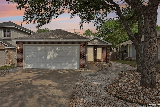 view of front facade with concrete driveway, brick siding, roof with shingles, and a garage