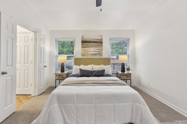 carpeted bedroom featuring baseboards, multiple windows, and ceiling fan