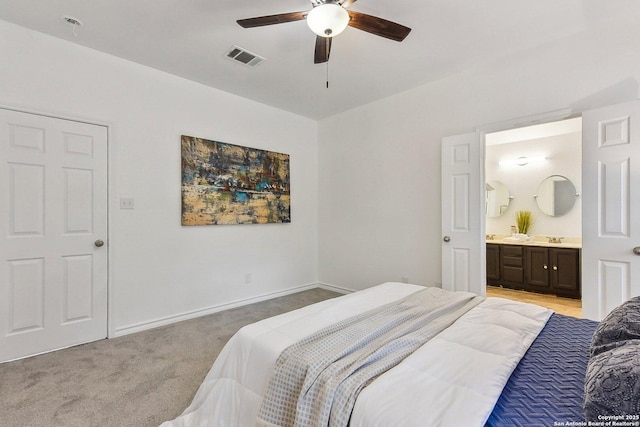 bedroom featuring visible vents, baseboards, ceiling fan, light colored carpet, and connected bathroom
