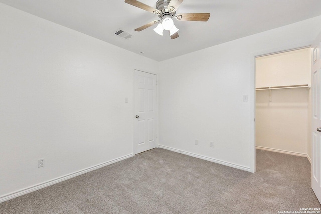 unfurnished bedroom featuring a ceiling fan, visible vents, carpet floors, baseboards, and a spacious closet