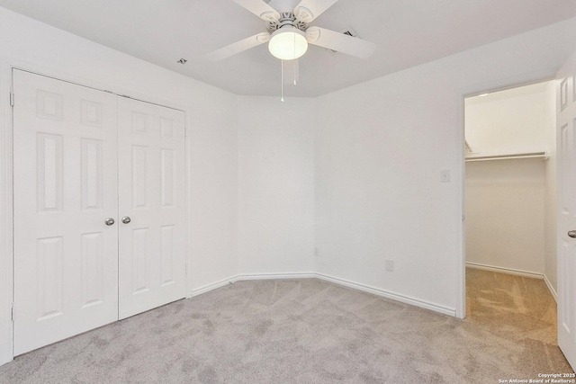 unfurnished bedroom with baseboards, a spacious closet, carpet, and a closet
