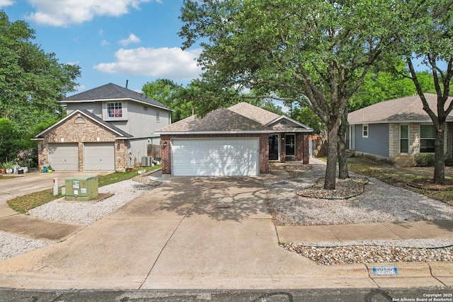 view of front facade featuring brick siding, central AC unit, an attached garage, and driveway