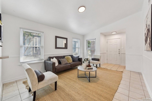 living room with light tile patterned floors, baseboards, and vaulted ceiling
