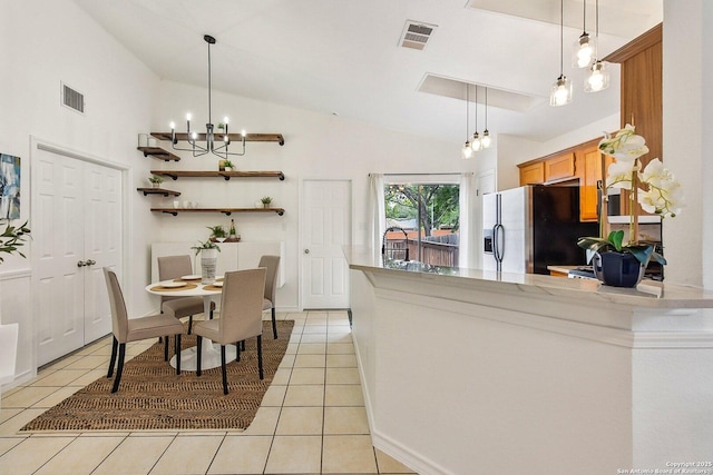 kitchen with visible vents, light tile patterned floors, fridge with ice dispenser, a peninsula, and a notable chandelier