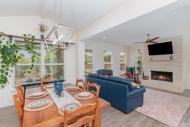 1420 Persimmon Pass, Fischer, TX 78623 - dining space with an outdoor stone fireplace, light wood-style flooring, ceiling fan with notable chandelier, baseboards, and vaulted ceiling with beams