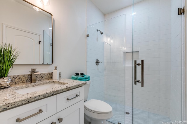 full bathroom featuring vanity, a shower stall, and toilet