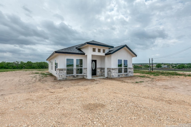 back of property featuring a shingled roof, stone siding, and stucco siding