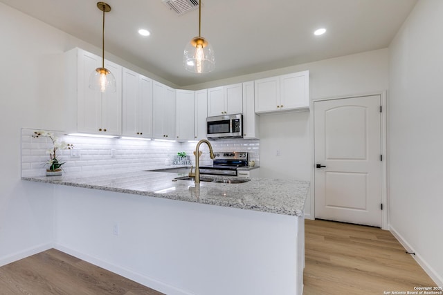 kitchen with visible vents, a peninsula, white cabinets, light stone counters, and stainless steel appliances