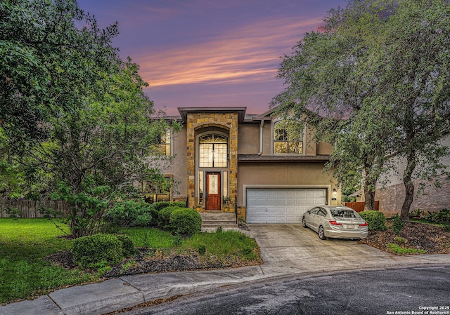 traditional home featuring driveway, a front yard, a garage, fence, and stucco siding