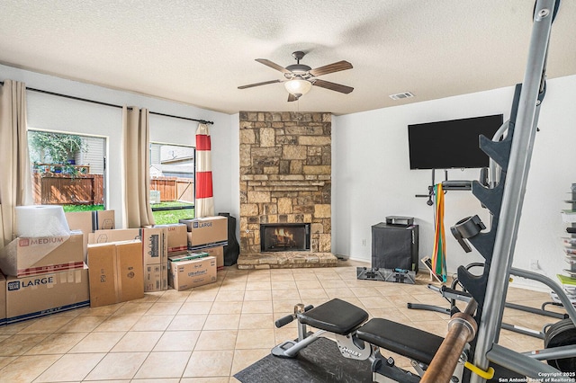exercise room featuring a textured ceiling, ceiling fan, visible vents, and a fireplace