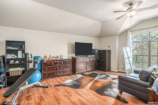living room with a ceiling fan, vaulted ceiling, and wood finished floors