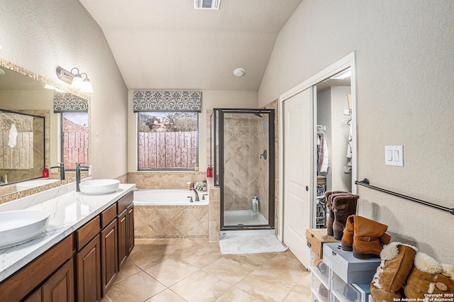full bath featuring tile patterned flooring, a garden tub, a sink, a stall shower, and vaulted ceiling