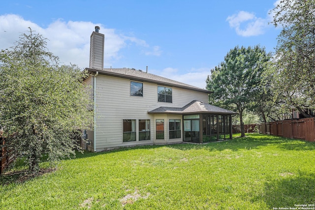 back of property featuring a sunroom, a lawn, a chimney, and fence private yard