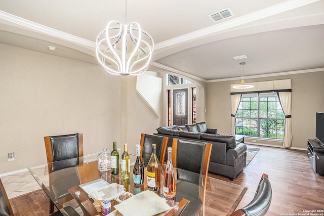 dining area featuring arched walkways, ornamental molding, a notable chandelier, and visible vents