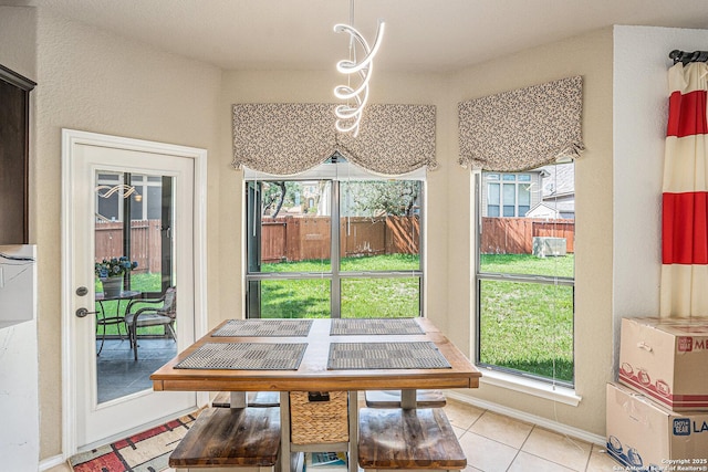dining room with a healthy amount of sunlight, light tile patterned floors, and baseboards