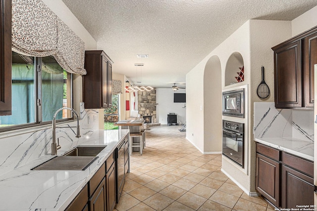kitchen with oven, dark brown cabinetry, open floor plan, and a sink