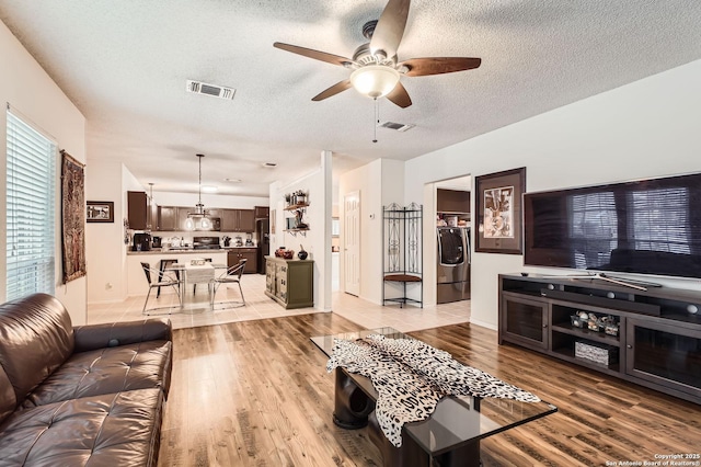 living area with ceiling fan, a textured ceiling, and visible vents