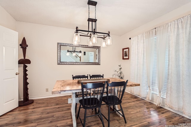 dining area featuring dark wood-type flooring, baseboards, and a chandelier