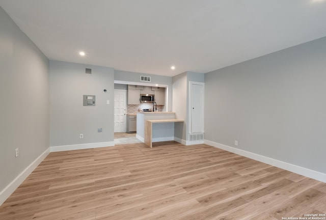 66 Brees Blvd Unit 125, San Antonio, TX 78209 - unfurnished living room featuring baseboards, visible vents, and light wood-style flooring