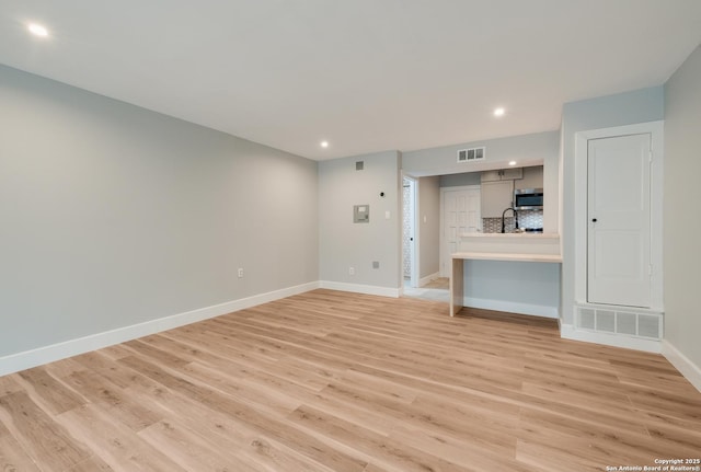 66 Brees Blvd Unit 125, San Antonio, TX 78209 - unfurnished living room featuring a sink, light wood finished floors, recessed lighting, baseboards, and visible vents