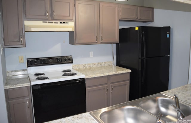 kitchen featuring range with electric stovetop, a sink, light countertops, freestanding refrigerator, and under cabinet range hood