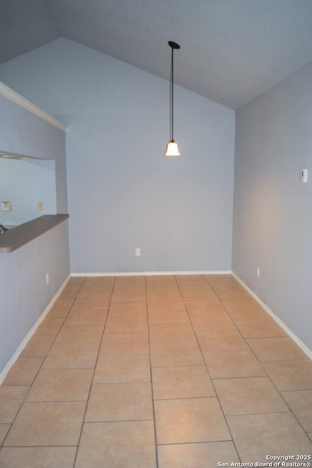 unfurnished room featuring baseboards, light tile patterned flooring, and vaulted ceiling
