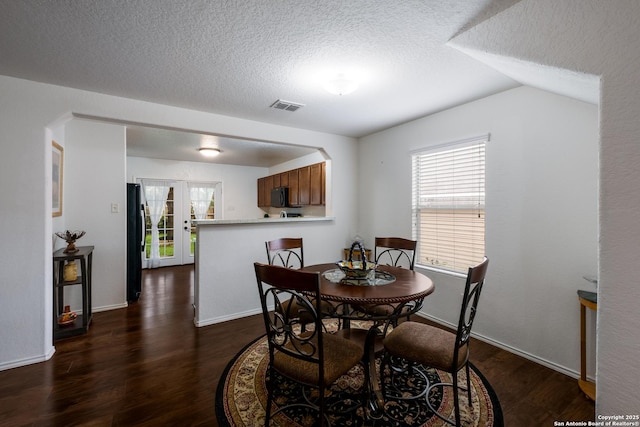 dining area with a textured ceiling, dark wood finished floors, baseboards, and visible vents