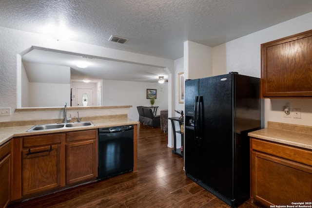 kitchen featuring visible vents, dark wood-style floors, a textured ceiling, a sink, and black appliances