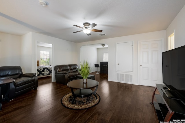 living area with ceiling fan, visible vents, and dark wood-type flooring