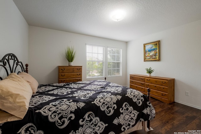 bedroom featuring baseboards, a textured ceiling, and dark wood-style flooring
