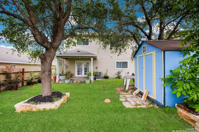 back of house featuring a lawn, an outbuilding, french doors, and a shed