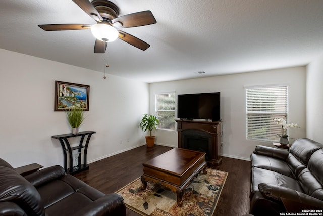 living area with a ceiling fan, visible vents, dark wood finished floors, and a fireplace