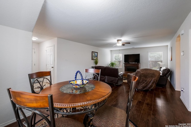 dining space with baseboards, a ceiling fan, wood finished floors, and a fireplace