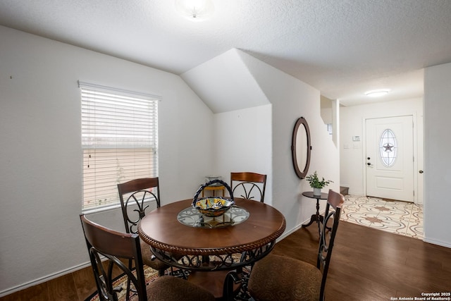 dining area featuring baseboards, wood finished floors, and vaulted ceiling